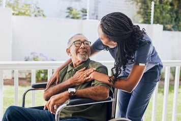 nurse talking to elderly man in wheelchair